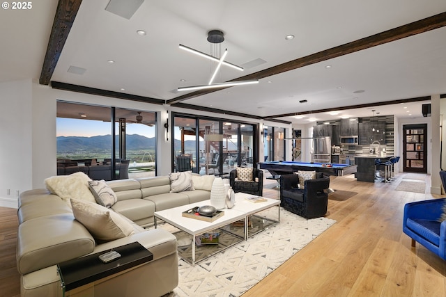 living room featuring beam ceiling, a mountain view, light wood-type flooring, and billiards