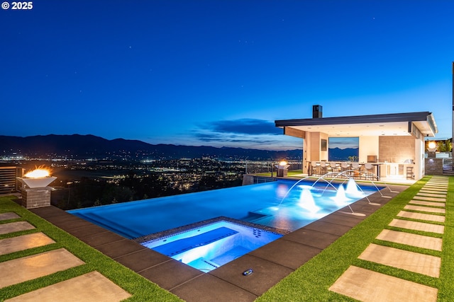 pool at dusk featuring exterior kitchen, an in ground hot tub, and exterior bar