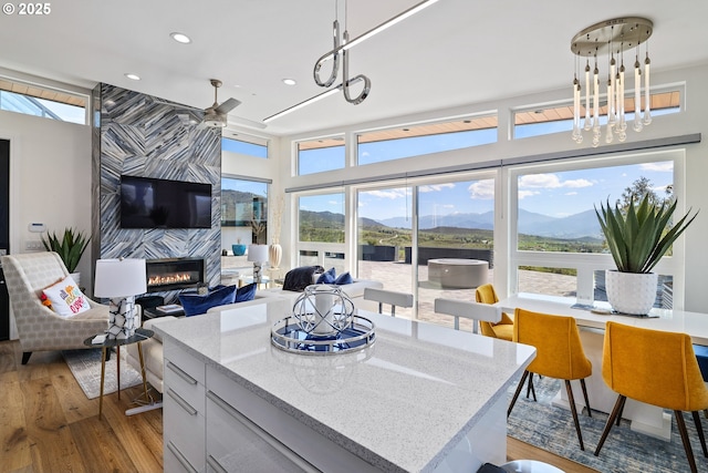 kitchen with hanging light fixtures, a kitchen island, a fireplace, and light hardwood / wood-style floors