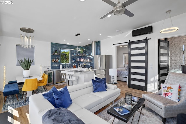 living room featuring wood-type flooring, a barn door, beverage cooler, and an AC wall unit