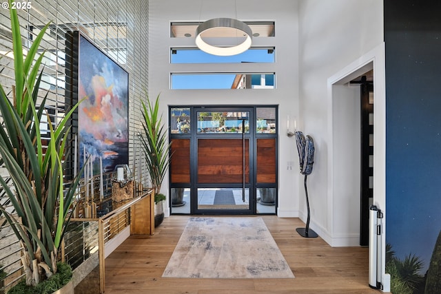 foyer entrance featuring a towering ceiling and light hardwood / wood-style floors