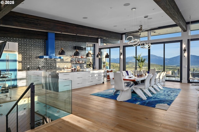 dining space with bar, a chandelier, a mountain view, beam ceiling, and light hardwood / wood-style floors