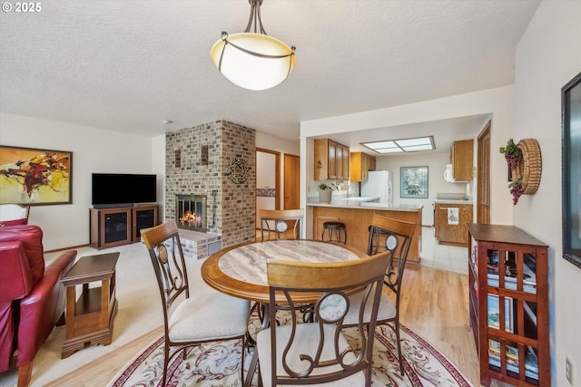 562 SW Eastman Pkwy, Gresham, OR 97080 - dining room featuring light wood-style floors, a fireplace, and a textured ceiling