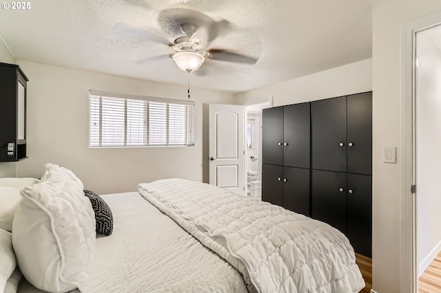 bedroom featuring a ceiling fan, a textured ceiling, wood finished floors, and a closet