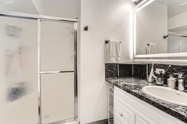 full bath with vanity, backsplash, and a stall shower