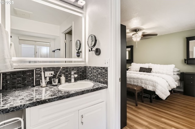 bathroom featuring vanity, ceiling fan, wood finished floors, and tasteful backsplash