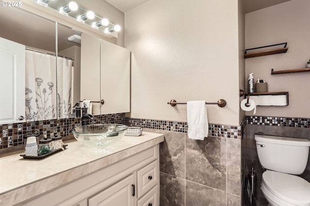 bathroom with vanity, tile walls, wainscoting, and toilet
