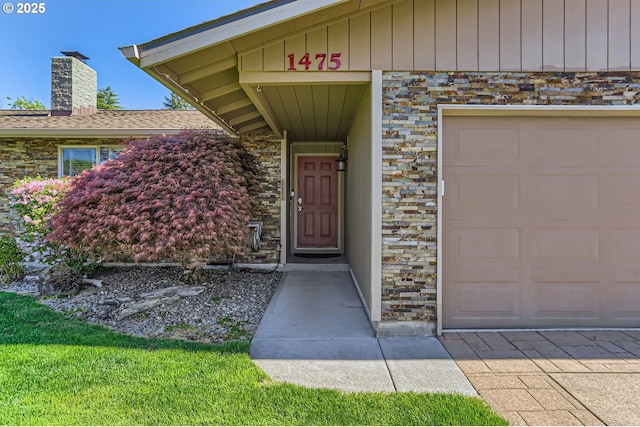 view of exterior entry featuring a garage, a chimney, and stone siding