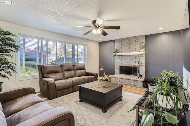 living area featuring plenty of natural light, a ceiling fan, wood finished floors, and a fireplace