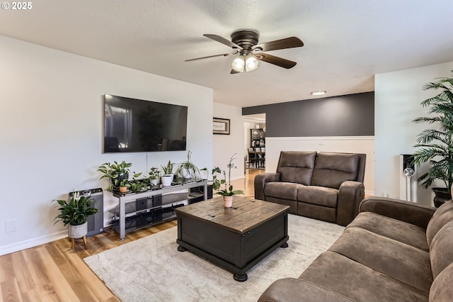 living room featuring a ceiling fan, baseboards, and light wood finished floors