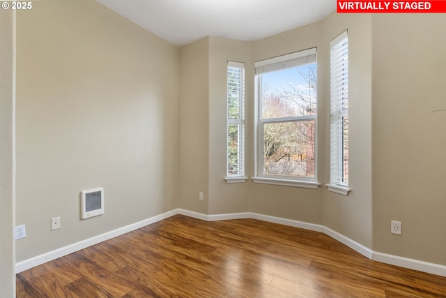 empty room featuring visible vents, wood finished floors, and a wealth of natural light