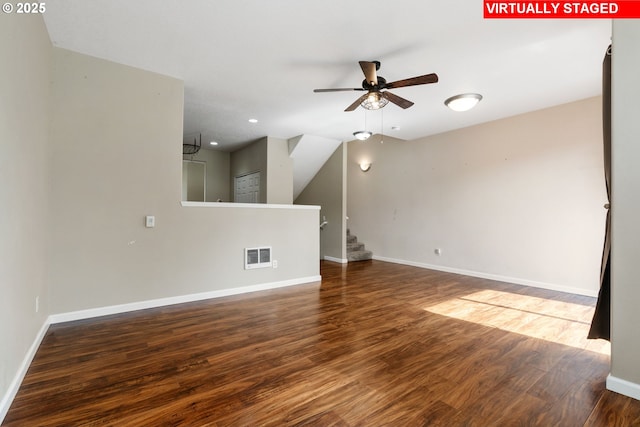 unfurnished room with visible vents, stairs, wood finished floors, baseboards, and ceiling fan