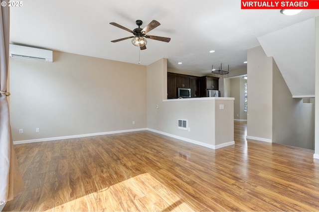 unfurnished living room featuring a ceiling fan, visible vents, an AC wall unit, light wood finished floors, and recessed lighting