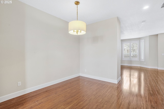 empty room with wood-type flooring and a textured ceiling