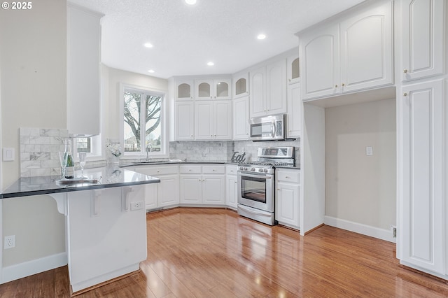 kitchen featuring white cabinetry, stainless steel appliances, sink, and light hardwood / wood-style flooring