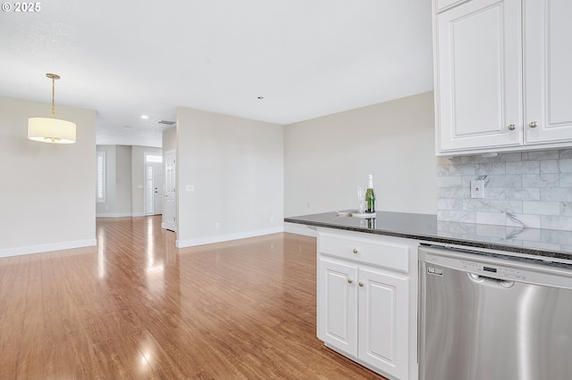 kitchen featuring pendant lighting, light hardwood / wood-style flooring, white cabinetry, decorative backsplash, and stainless steel dishwasher