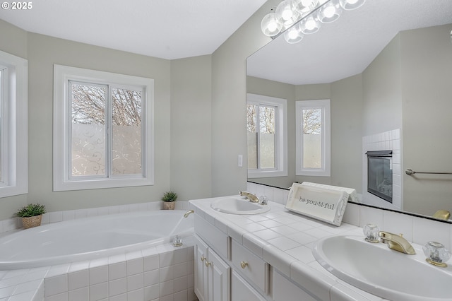 bathroom featuring a relaxing tiled tub, vanity, and a tile fireplace