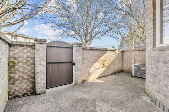 view of gate featuring central AC unit and a patio area