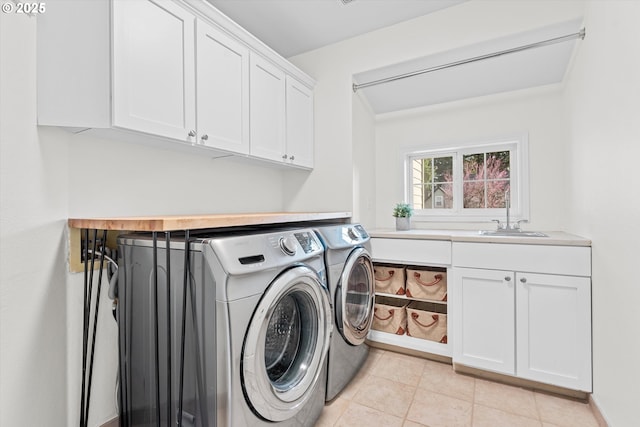 laundry room featuring light tile patterned floors, cabinet space, separate washer and dryer, and a sink