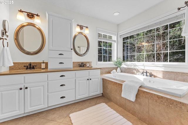 full bath with tile patterned flooring, a garden tub, double vanity, and a sink