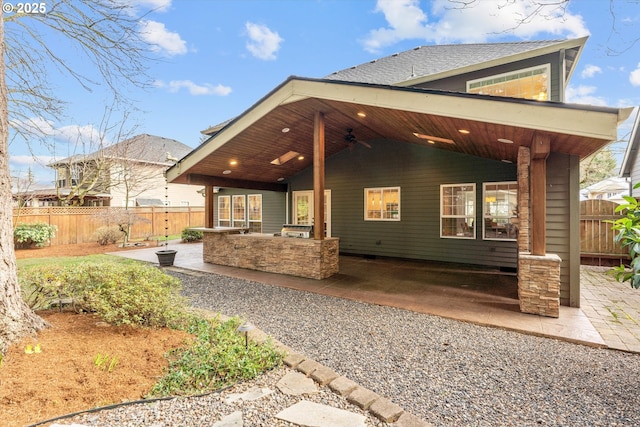 rear view of house with fence, exterior kitchen, a ceiling fan, and a patio area