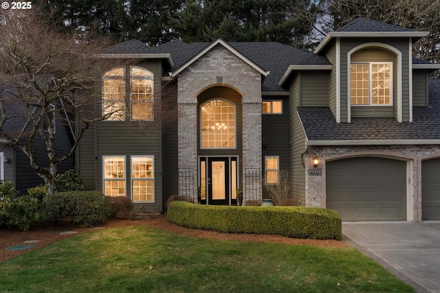 view of front of house with a front yard, driveway, roof with shingles, an attached garage, and brick siding