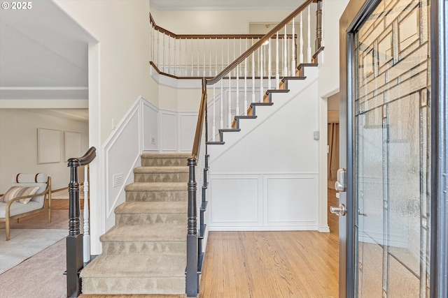 interior space with stairs, a decorative wall, light wood-style flooring, and a high ceiling