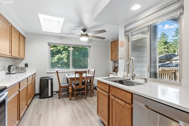14938 SW 109th Ave, Portland, OR 97224 - kitchen featuring stainless steel dishwasher, a sink, light wood-type flooring, a skylight, and light countertops