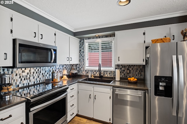 440 S Cascade Dr, Woodburn, OR 97071 - kitchen with appliances with stainless steel finishes, a sink, dark countertops, a textured ceiling, and crown molding