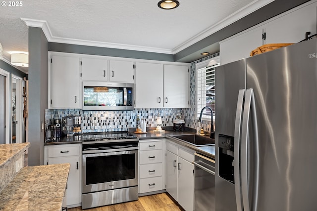 440 S Cascade Dr, Woodburn, OR 97071 - kitchen featuring appliances with stainless steel finishes, a sink, crown molding, and white cabinets