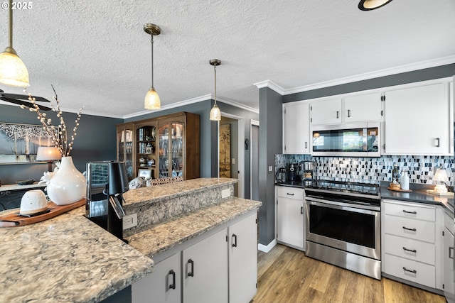 440 S Cascade Dr, Woodburn, OR 97071 - kitchen featuring appliances with stainless steel finishes, light wood finished floors, decorative backsplash, crown molding, and white cabinets