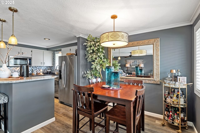 440 S Cascade Dr, Woodburn, OR 97071 - dining space featuring wood finished floors, bar, ornamental molding, healthy amount of natural light, and baseboards