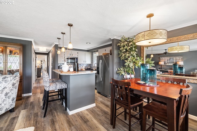 440 S Cascade Dr, Woodburn, OR 97071 - dining space with ornamental molding, dark wood-type flooring, ceiling fan, a textured ceiling, and baseboards