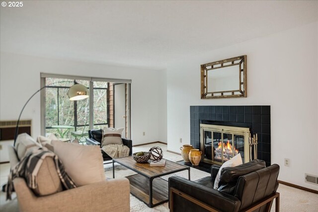 living area featuring light carpet, visible vents, baseboards, and a tile fireplace