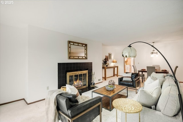 carpeted living area with a tiled fireplace, baseboards, and a chandelier