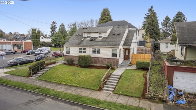 view of front of property with brick siding, a front lawn, fence, a residential view, and roof with shingles