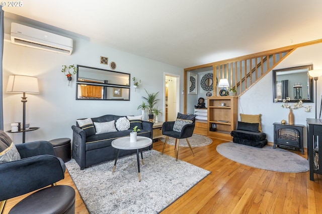 living room with stairway, light wood-style flooring, a wood stove, and a wall unit AC