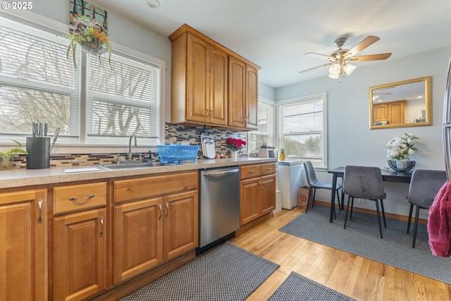 kitchen with a sink, decorative backsplash, light countertops, light wood-style floors, and stainless steel dishwasher