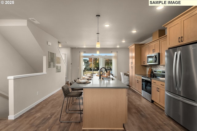 kitchen with sink, appliances with stainless steel finishes, hanging light fixtures, an island with sink, and light brown cabinets