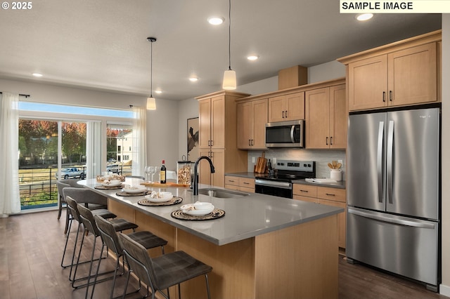 kitchen featuring sink, decorative light fixtures, light brown cabinets, an island with sink, and stainless steel appliances