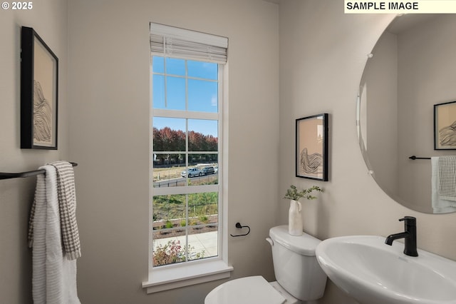 bathroom featuring a healthy amount of sunlight, sink, and toilet