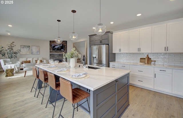 kitchen with stainless steel refrigerator with ice dispenser, white cabinetry, decorative light fixtures, and gray cabinets