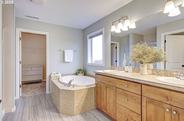 bathroom featuring vanity and tiled bath