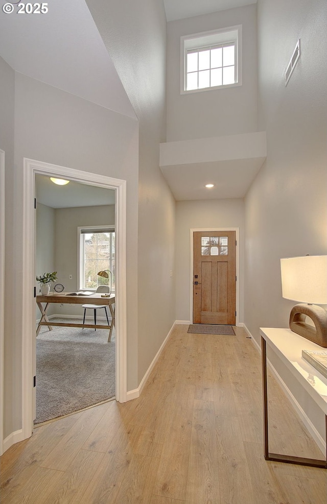 foyer entrance featuring light hardwood / wood-style floors and a high ceiling