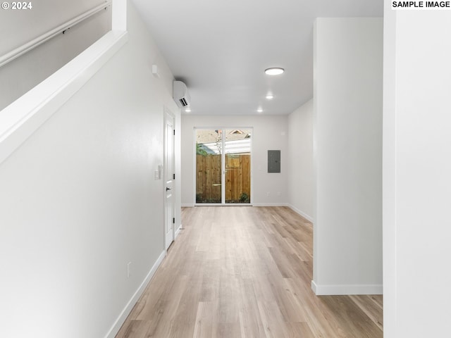 hall with electric panel, a wall unit AC, and light hardwood / wood-style flooring