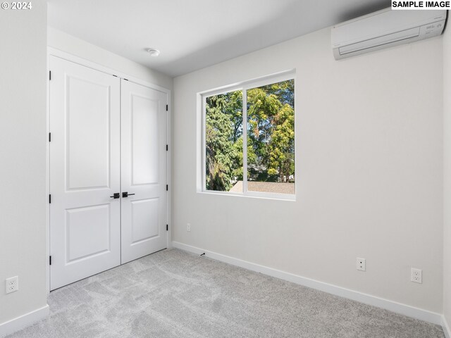 unfurnished bedroom featuring light carpet, a wall unit AC, and a closet