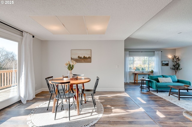 dining area featuring wood-type flooring and a textured ceiling