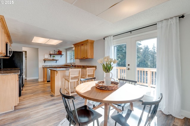 dining room with sink, a textured ceiling, light hardwood / wood-style floors, and french doors