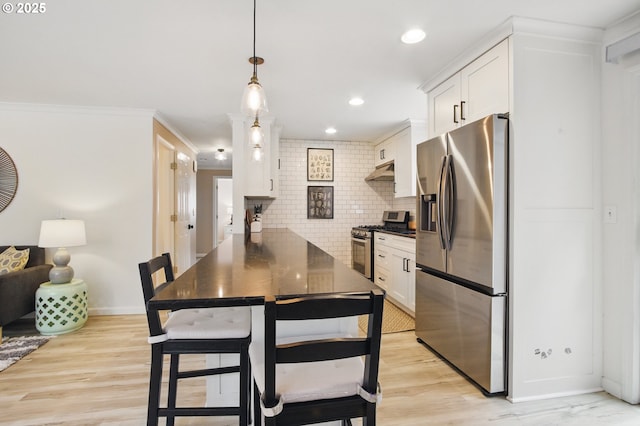 kitchen featuring white cabinetry, decorative backsplash, appliances with stainless steel finishes, and under cabinet range hood