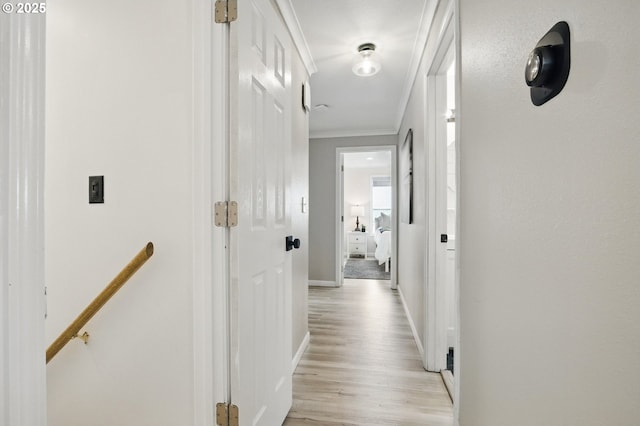 corridor featuring baseboards, ornamental molding, an upstairs landing, and light wood-type flooring